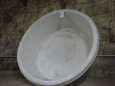 un grand saladier blanc posé par terre dans une pièce