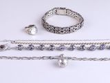 three pieces of silver jewelry on a white surface