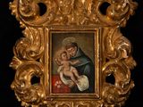an ornate gold frame with a painting of a woman holding a child
