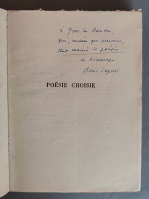 un livre ouvert, sur lequel est inscrit un poème manuscrit, posé sur une table