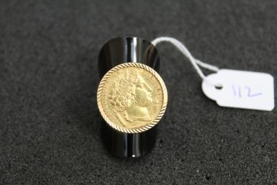 Gros plan sur une bague ornée d'une pièce d'or