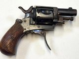 un vieux revolver avec une poignée en bois sur une surface blanche