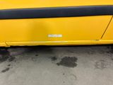 a close up of a yellow car parked in a parking lot