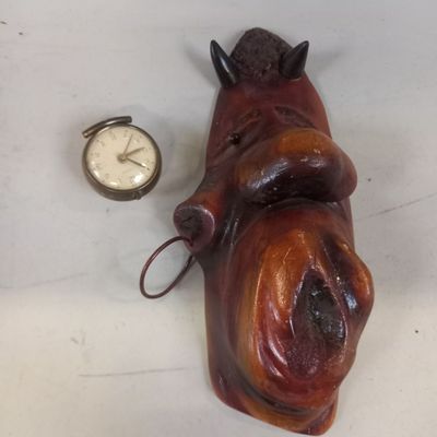 statue représentant un chien couché à côté d'une montre de poche posée sur une table