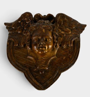 une image représentant une plaque en bronze sur laquelle figurent un visage et des ailes