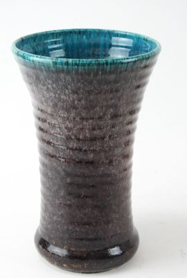 a close up of a blue and black vase on a white surface