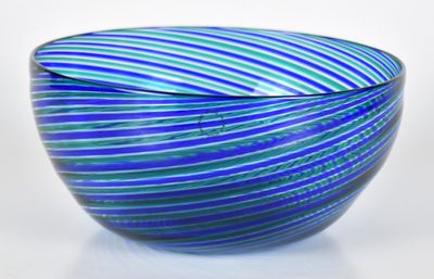 un saladier en verre rayé de bleu et de vert posé sur une surface blanche