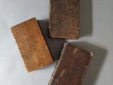 three old books sitting on top of a table next to each other