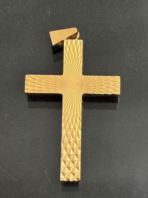 a close up of a gold cross on a black surface