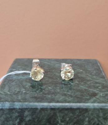 une paire de boucles d'oreilles à clous en diamant jaune posée sur une table en marbre