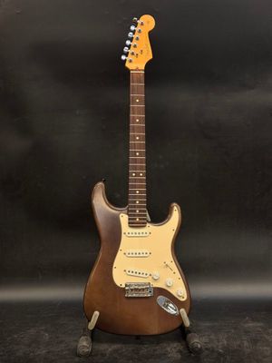 an electric guitar on a stand against a black background