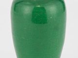 un vase vert posé sur un socle en bois