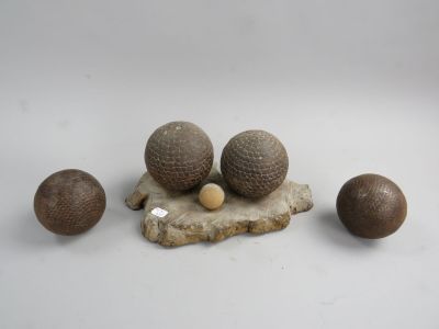 trois boules en bois et une boule en bois posée sur un rocher, le tout sur une surface blanche