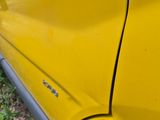 a close up of a yellow car parked on the side of the road