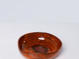 un bol marron posé sur une table blanche, sur fond blanc