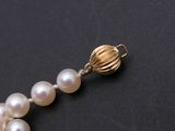 a close up of a white pearl necklace on a black surface