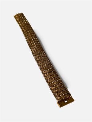 le bracelet en métal doré est posé sur un fond blanc