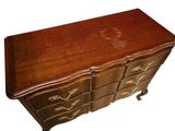 a wooden chest of drawers with gold decorations on it