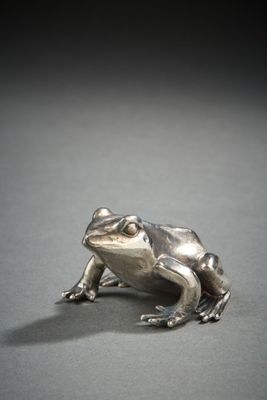 figurine en argent représentant une grenouille assise sur une surface grise