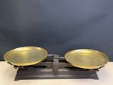 two brass plates on a wooden stand on a table