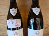 two bottles of wine sitting on a shelf next to each other