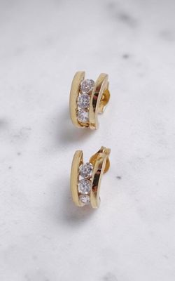 une paire de boucles d'oreilles en or et diamants posée sur une surface en marbre