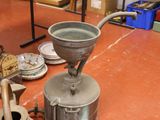 a large metal pot sitting on the floor next to a table