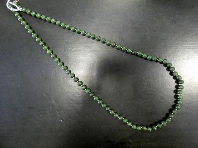 un gros plan sur un collier de perles vertes porté par un mannequin