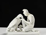 une statue blanche représentant un homme et un oiseau, posée sur une table