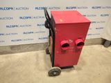 the red machine is sitting in front of a wall with a sign behind it