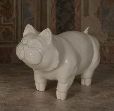 une statue de cochon blanc posée par terre devant un mur