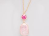 un pendentif en pierre rose avec une chaîne en or sur fond blanc
