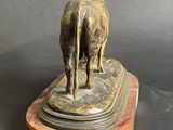 statue of a bull standing on a marble base on a black background