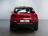 the rear of a red car is parked in a large room