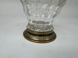 a glass vase with a gold base on a white surface