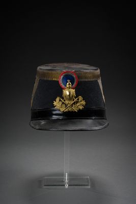 a black hat with a gold emblem on it sitting on a stand