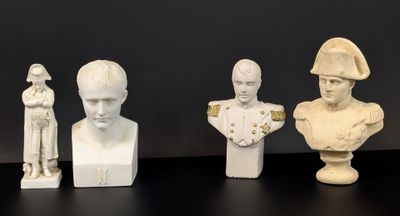 trois busturines blanches de tailles et de formes différentes posées sur une surface noire