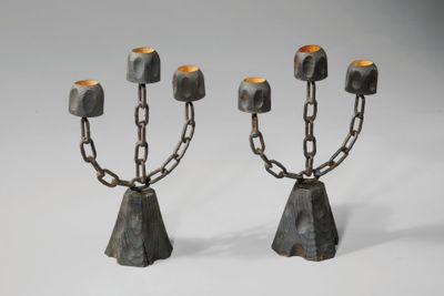 une paire de bougeoirs en métal ornés de chaînes, sur fond blanc