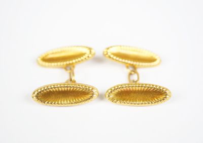 a pair of gold cufflinks with oval design