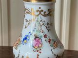 a white vase on a table with gold trimming