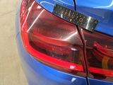 a close up of a blue car with a sticker on it ' s tail light