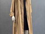 a mannequin wearing a tan trench coat and black dress