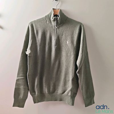 a close up of a sweater hanging on a hanger on a wall