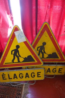deux panneaux de signalisation jaunes et rouges posés sur une table en bois