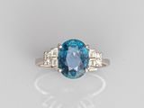 a close up of a blue diamond and diamond ring on a white surface