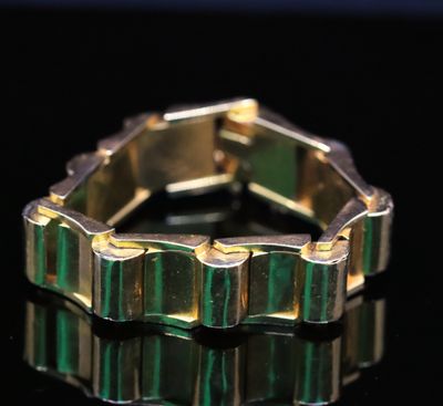 un gros plan d'une bague dorée et verte posée sur une surface noire