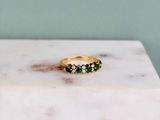 an image of a gold ring with emerald stones