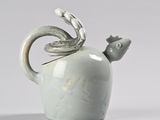 a white teapot with a bird on top of it