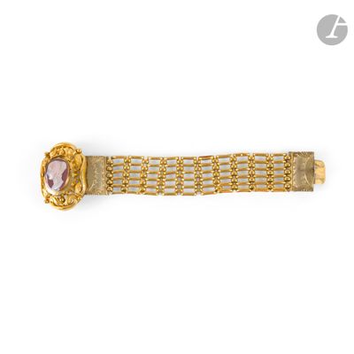 un gros plan sur un bracelet en or orné d'une pierre rose au centre