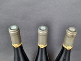 three bottles of wine are lined up on a gray surface